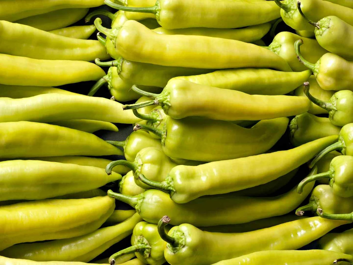 A close pile of pale green banana peppers