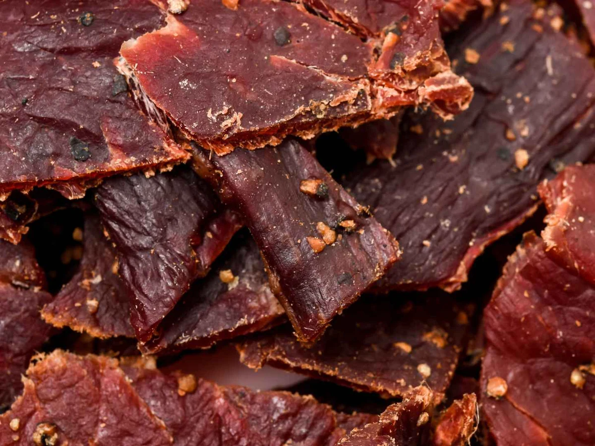 Dark seasoned beef jerky pieces piled in a close-up view.