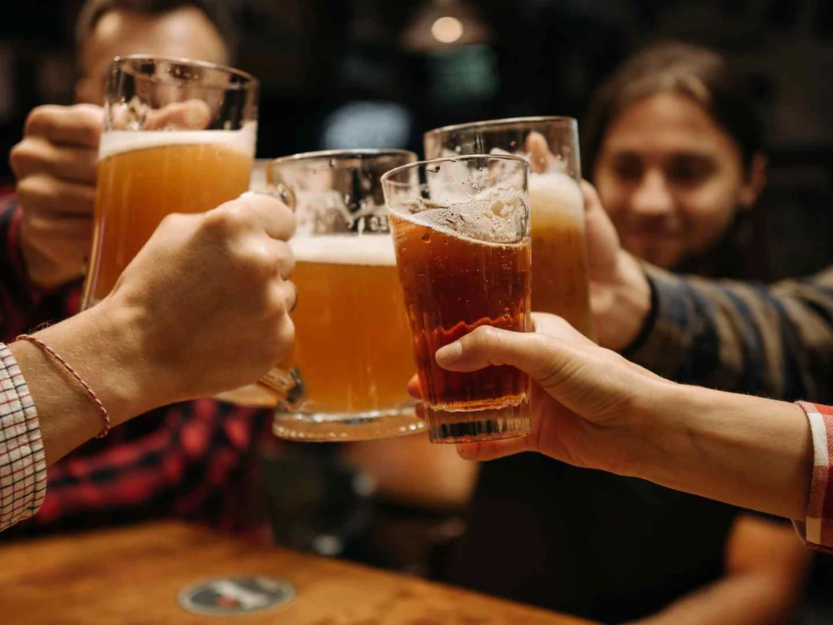 People clinking glasses of beer around a table