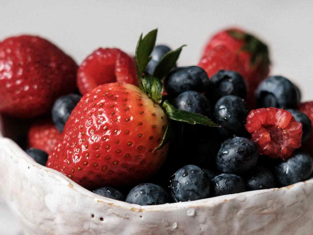 A white bowl containing strawberries, blueberries, raspberries, and blackberries.