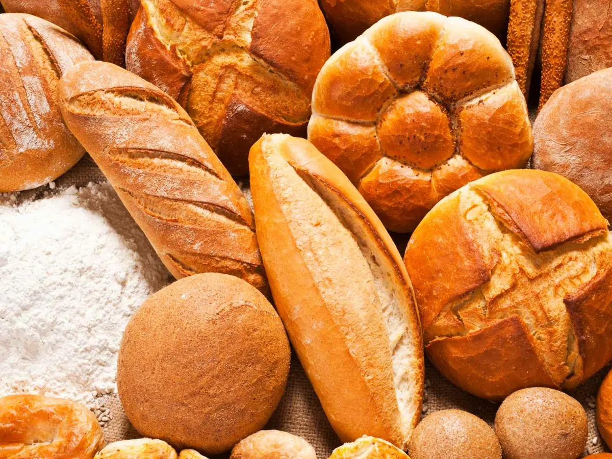 An assortment of rustic bread loaves, rolls, and flour