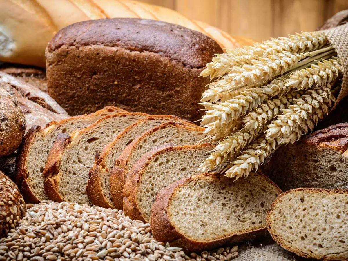 Sliced seeded bread, wheat stalks, and whole-grain loaves