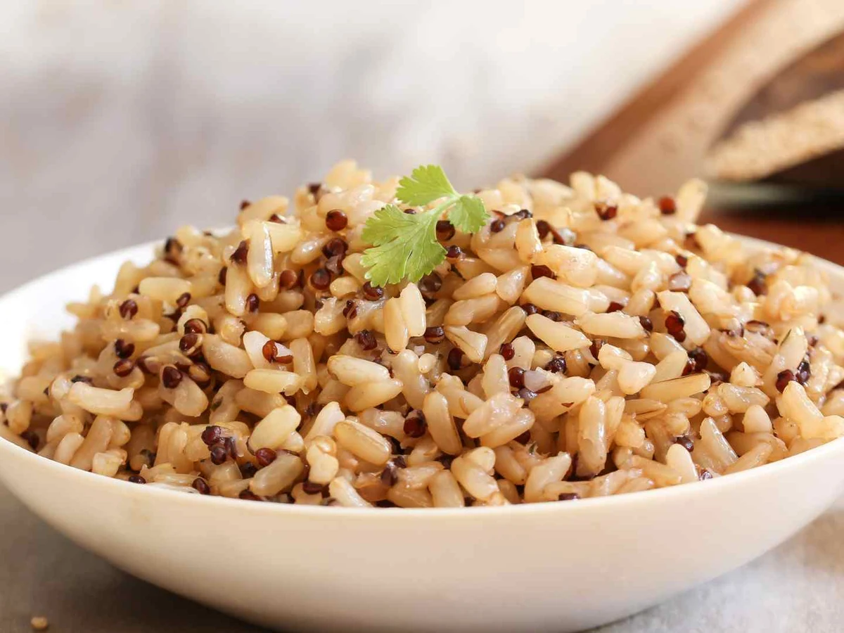 A bowl of cooked mixed brown rice and grains on a light table.