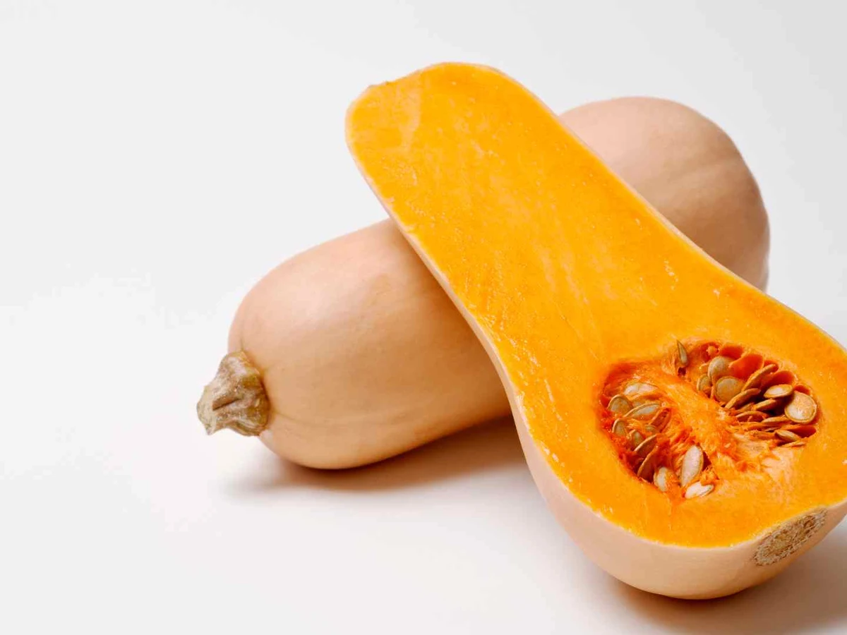 A halved butternut squash with seeds visible against a white background.