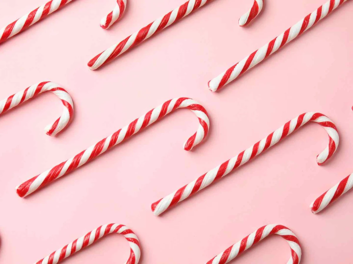Red and white candy canes arranged across a pink background