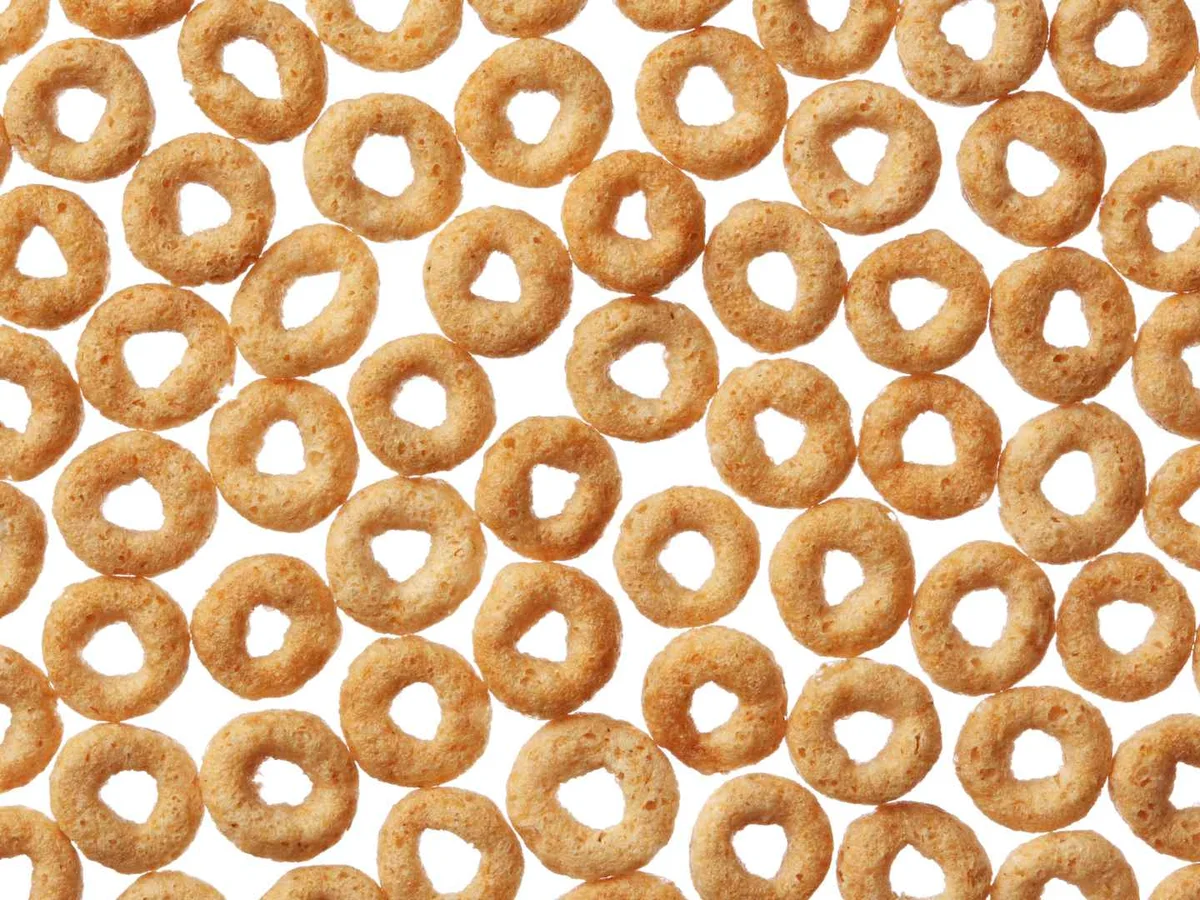 Rows of plain oat cereal rings arranged tightly on white.