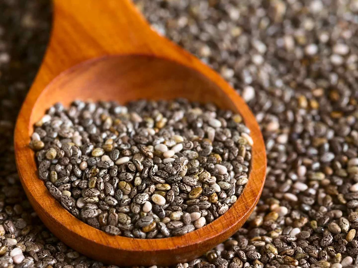 Chia seeds in a wooden spoon over more seeds