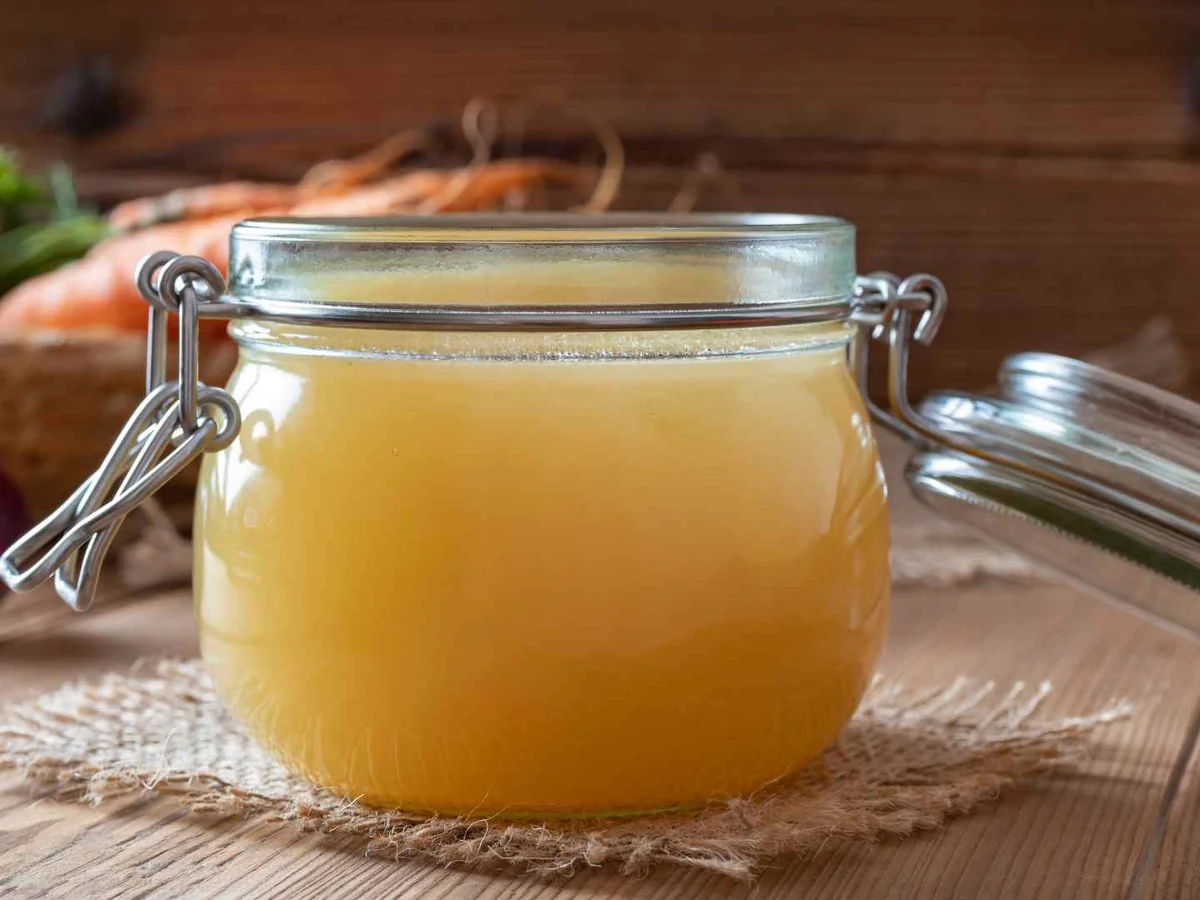 Golden chicken broth in a sealed glass jar