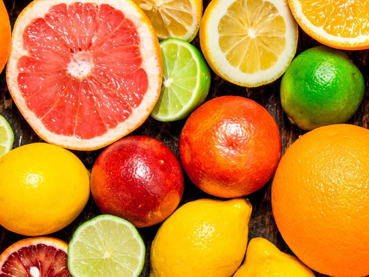 Whole and halved oranges, grapefruit, lemons, and limes filling the frame