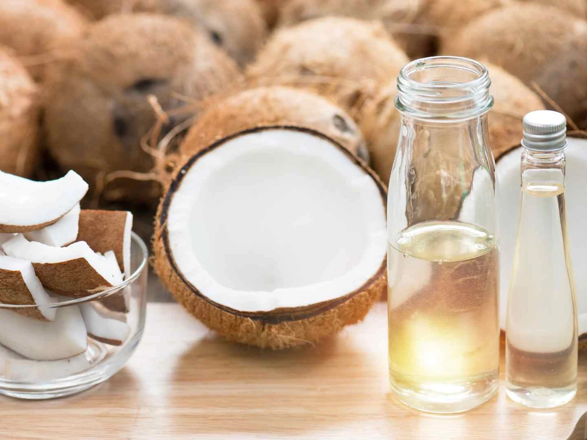 Coconut halves and broken shell pieces beside two bottles of clear liquid.
