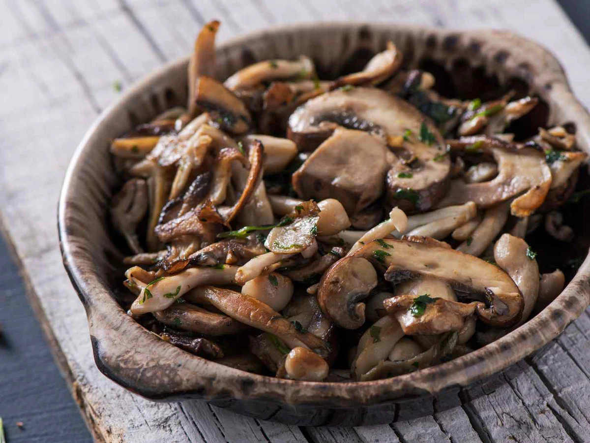 A rustic bowl filled with cooked sliced mushrooms.