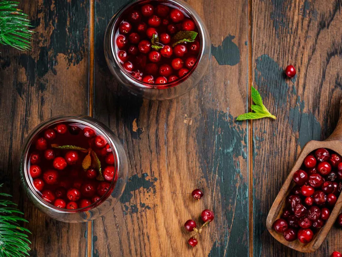 Fresh cranberries arranged in small wooden bowls with evergreen branches.