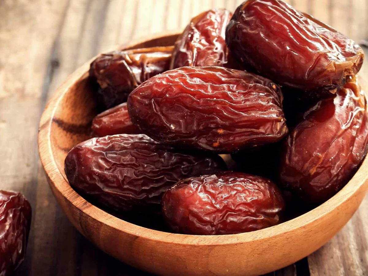 Glossy brown dates in a wooden bowl