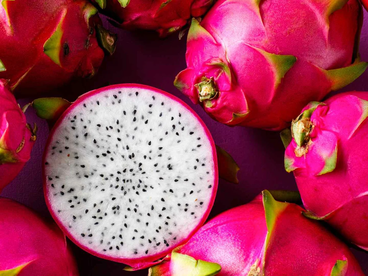 Whole dragon fruit surrounding a halved white-fleshed fruit