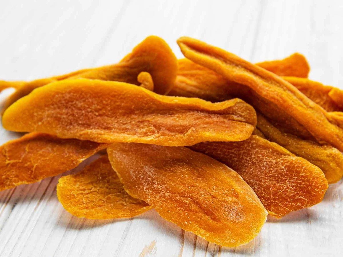 A small pile of dried mango slices against a white background.