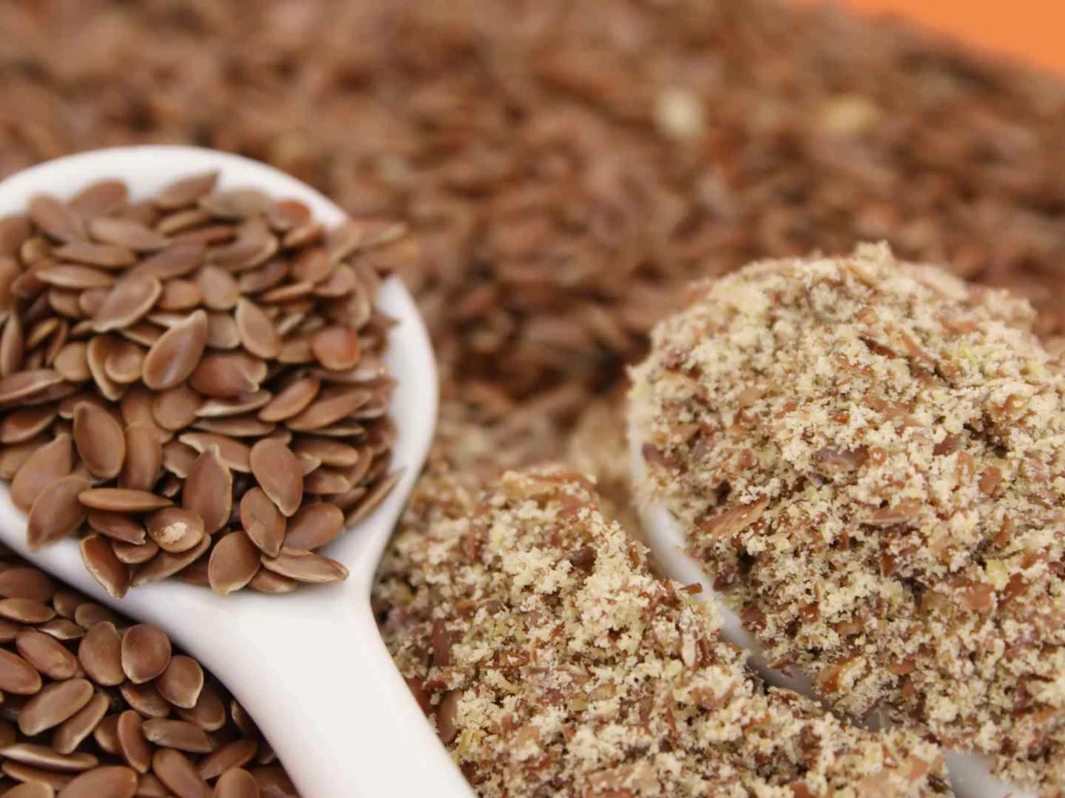 Whole flaxseed and ground flax meal in bowls and a spoon
