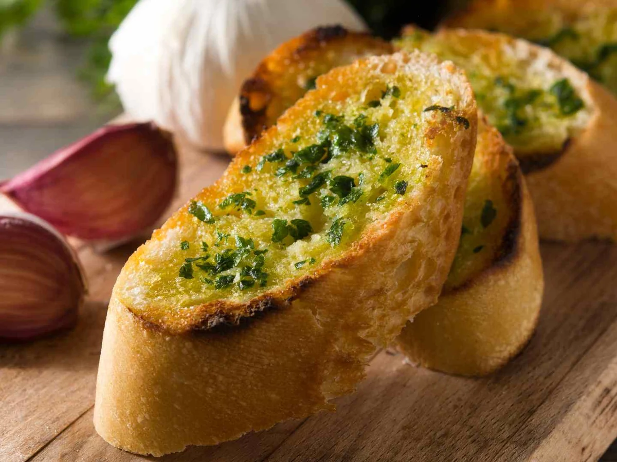 Garlic bread slices beside a whole garlic bulb