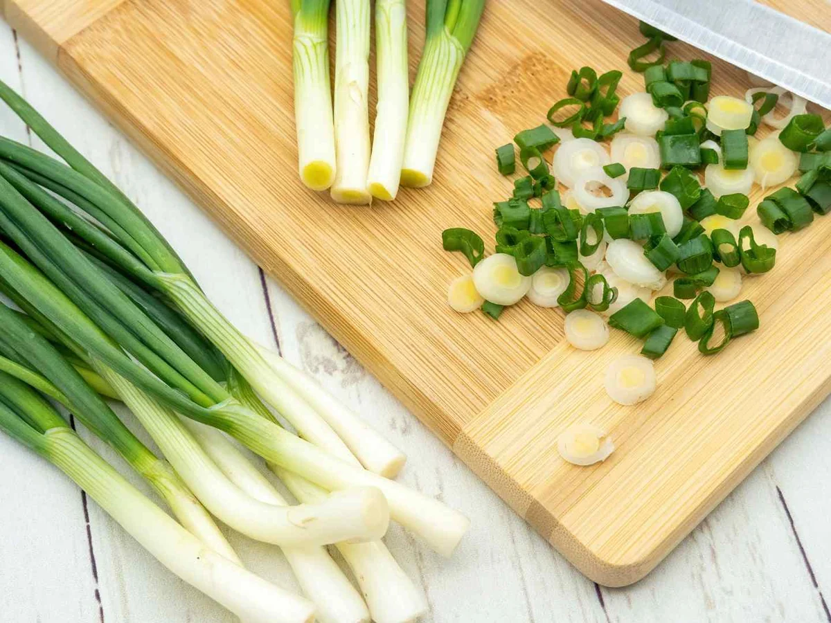 Green onions and chopped pieces beside a knife