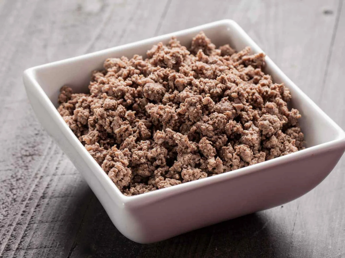 Cooked crumbled ground beef in a small white bowl