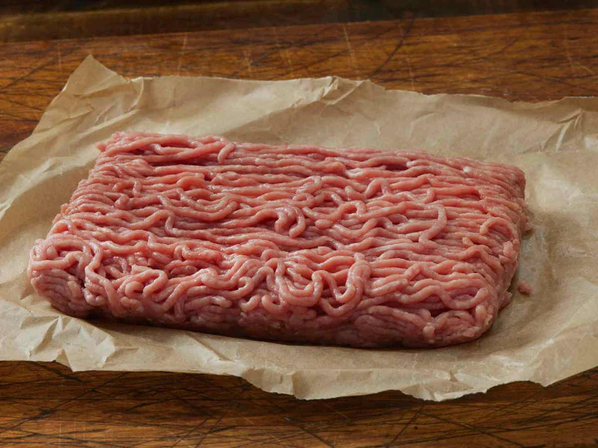 Raw ground turkey on butcher paper over a wooden table.
