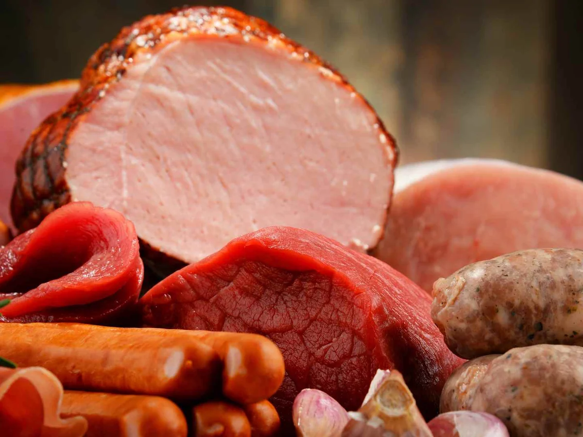 Sliced ham surrounded by sausages and other cooked meats