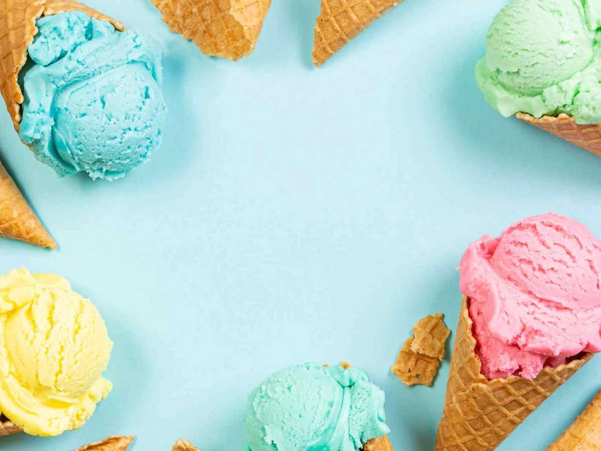Pastel ice cream scoops and overturned cones arranged on a pale blue background