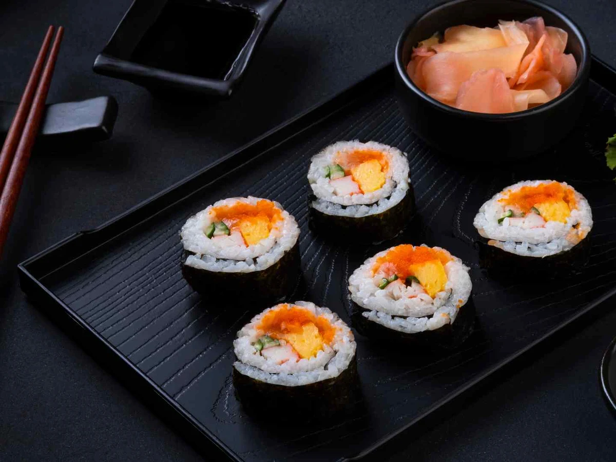 Red-and-white imitation crab sticks stacked on a dark stone surface.