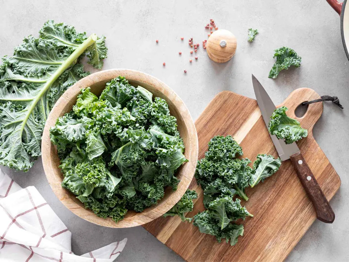 Chopped kale in a bowl beside a knife and towel