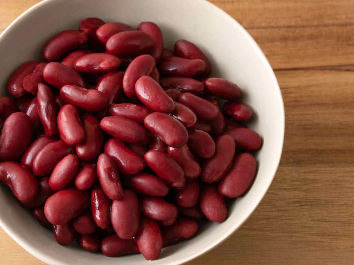 Red kidney beans heaped in a white bowl against white.