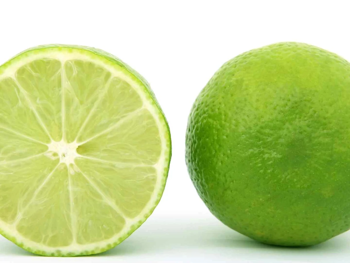 One whole lime and one lime half isolated on white