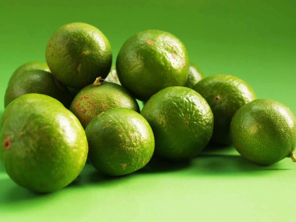 Whole green limes stacked on a green background