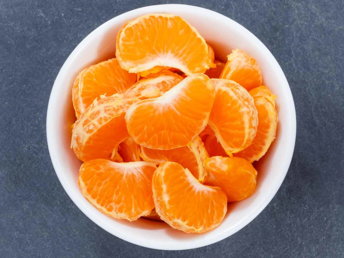 Peeled mandarin segments in a white bowl