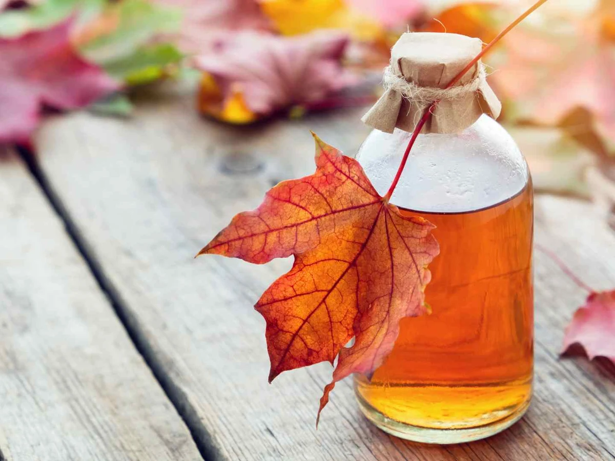 Amber maple syrup in a bottle decorated with a red maple leaf.