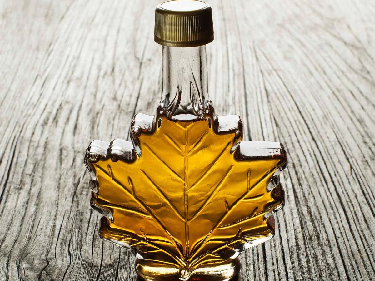 Amber syrup in a maple-leaf-shaped glass bottle.