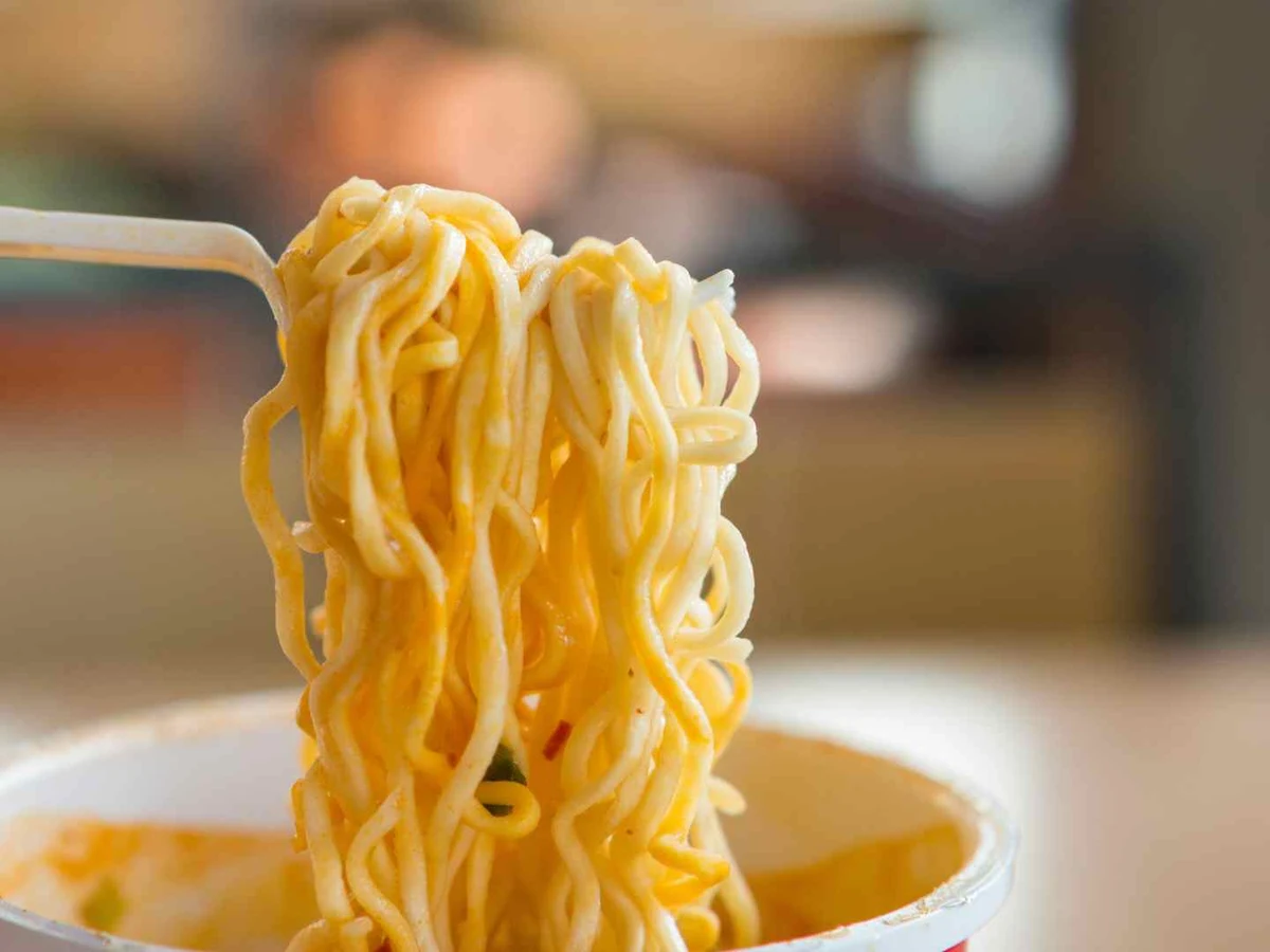Long noodles lifted with chopsticks from a bowl of broth.