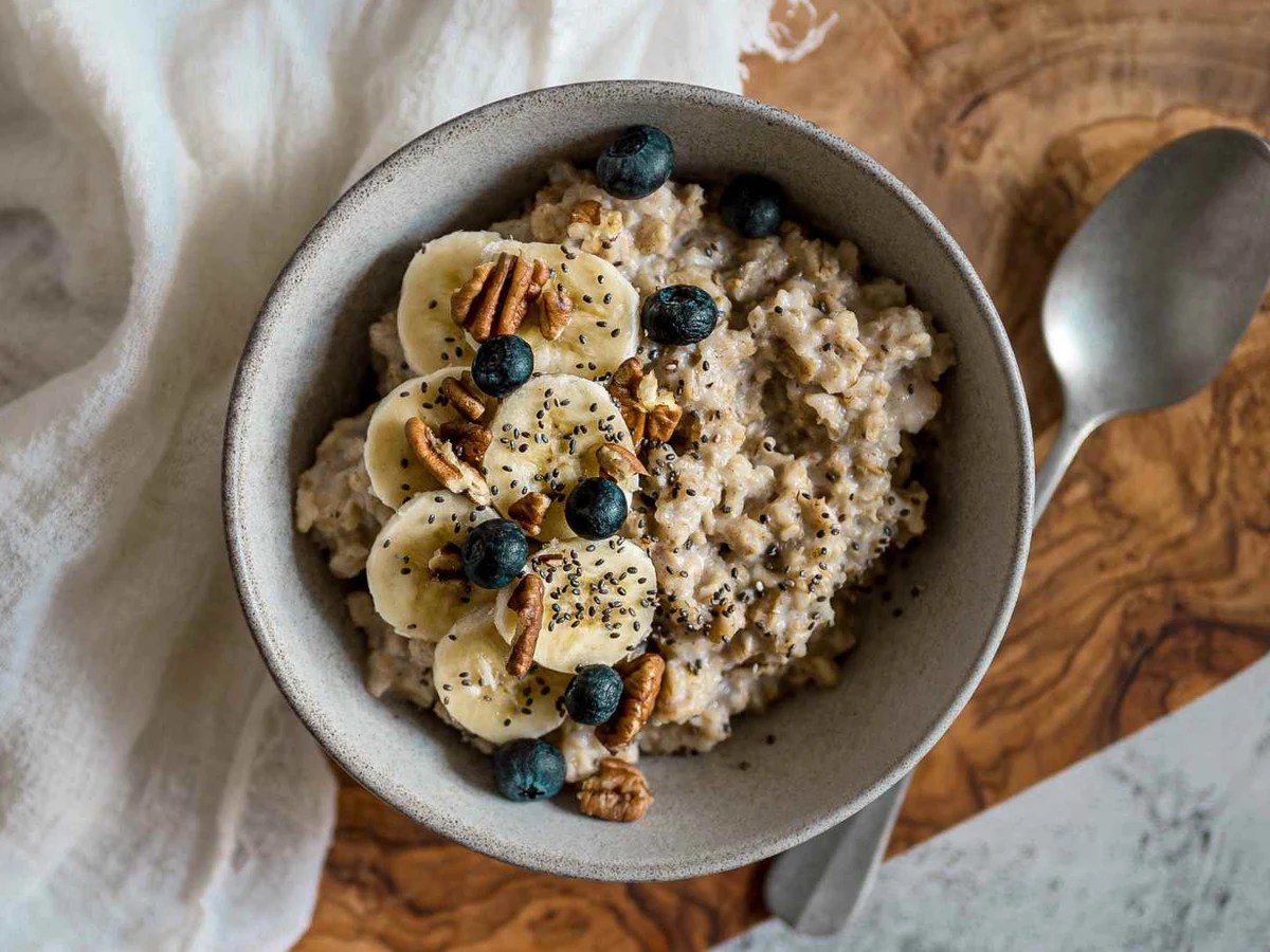 Oatmeal topped with banana slices, blueberries, chia seeds, and cinnamon in a gray bowl.