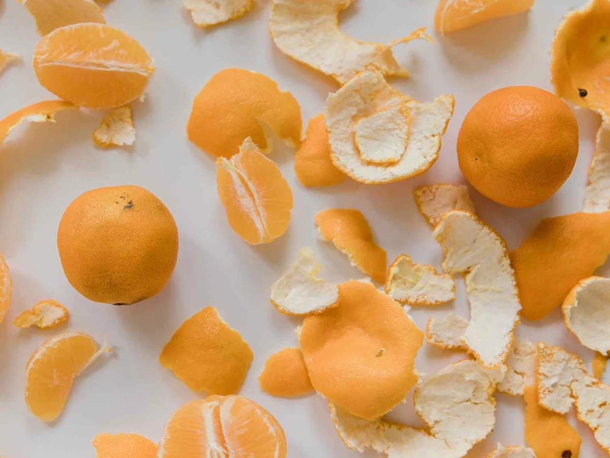 Mandarin peels and fruit pieces scattered on white