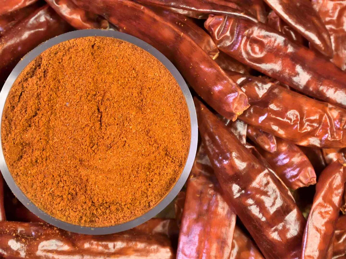 Paprika powder in a bowl surrounded by dried red peppers