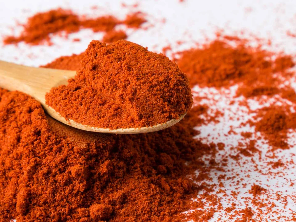 A wooden spoon heaped with paprika powder