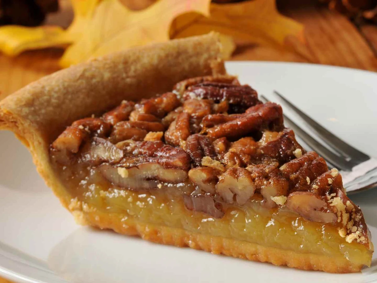 A single slice of pecan pie on a white plate
