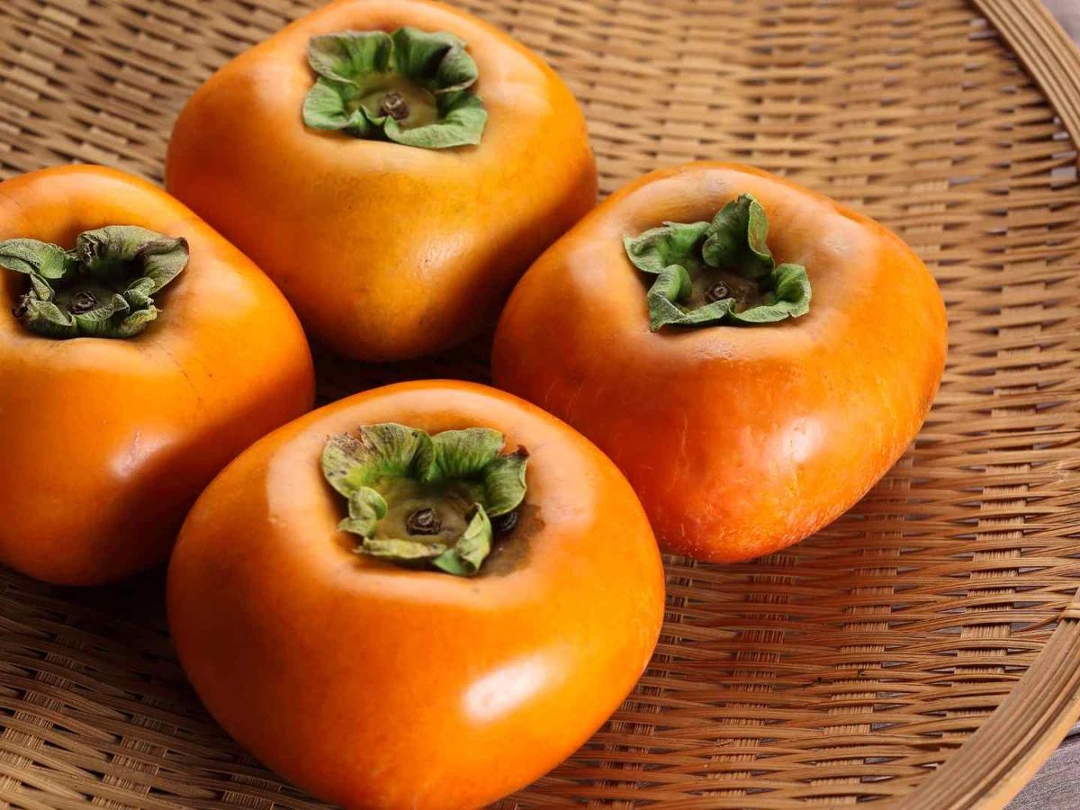 Ripe orange persimmons packed together at a market.