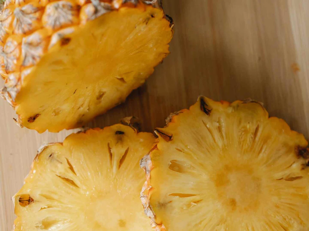 Pineapple rounds and rind pieces on a wooden cutting board.