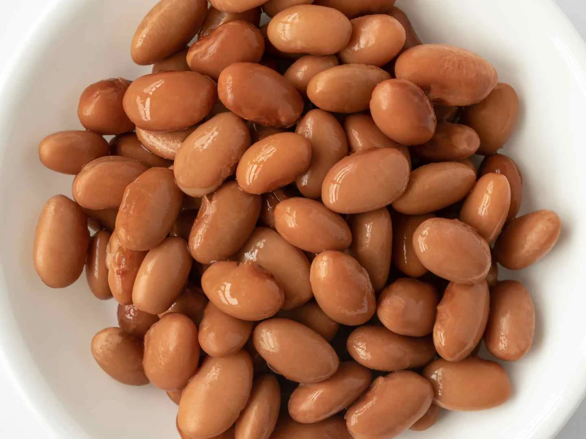 A white bowl of cooked pinto beans