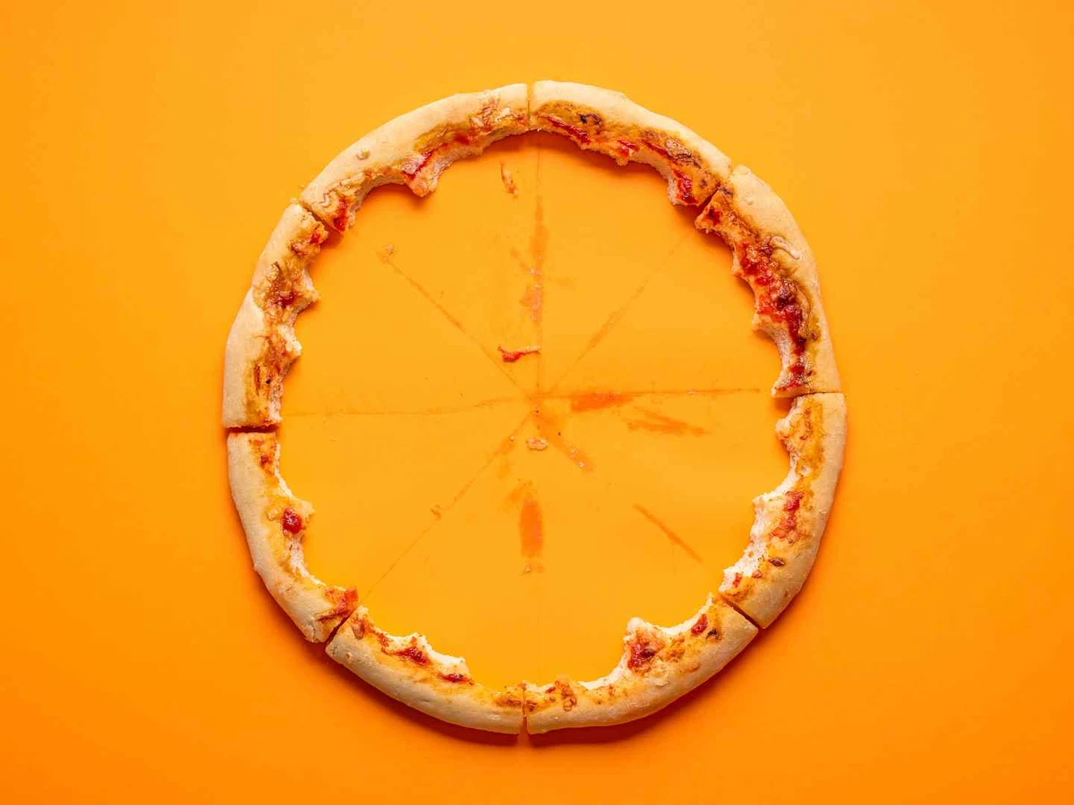 A bare circular pizza crust edge with crumbs on a blue background.
