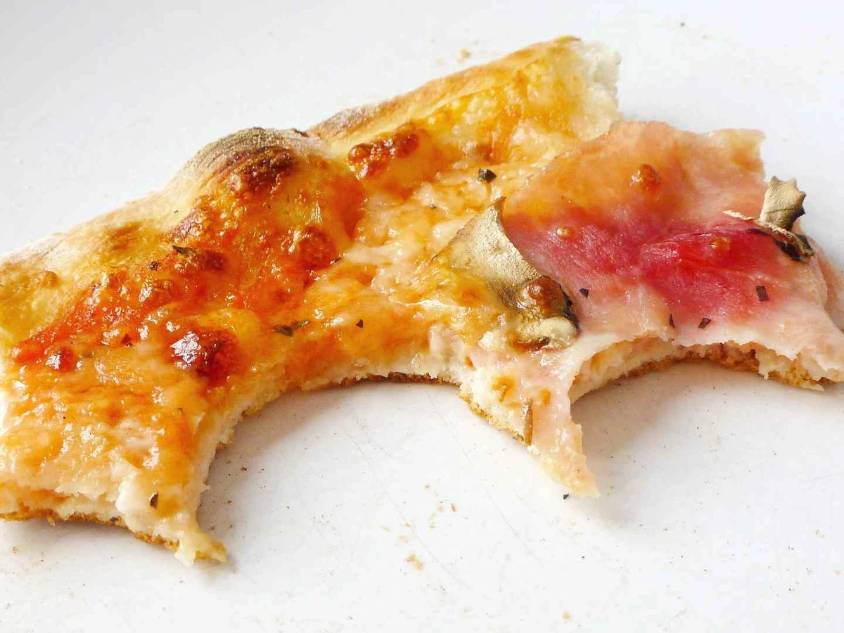 A bare circular pizza crust edge centered on an orange background.
