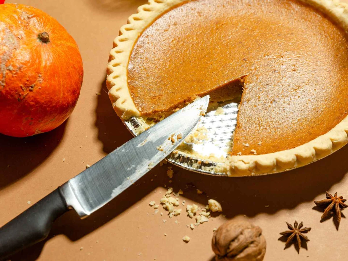 A plain slice of pumpkin pie topped with whipped cream.