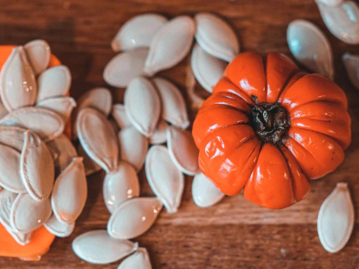Fresh pumpkin seeds and stringy pulp spilling from a cut pumpkin.