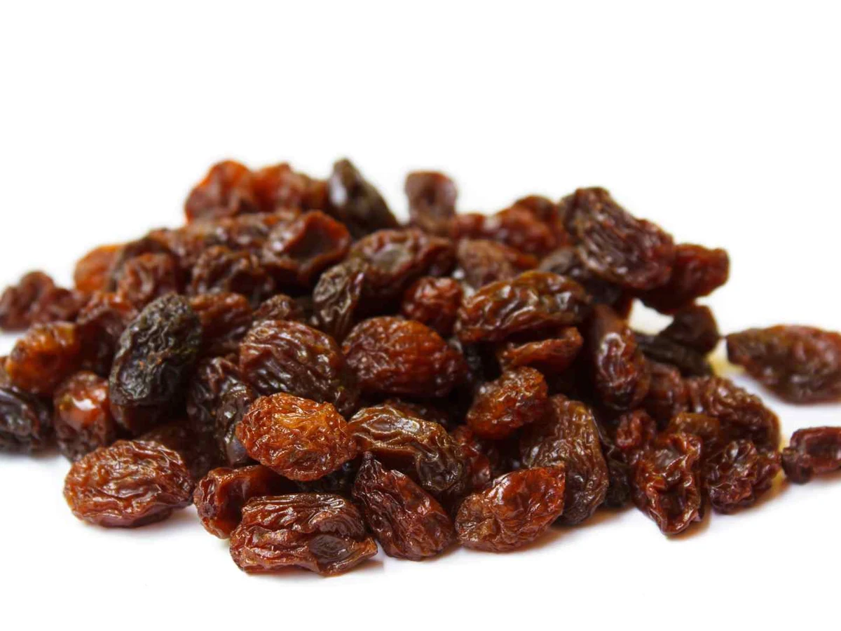 A loose pile of dark brown raisins on a white background.
