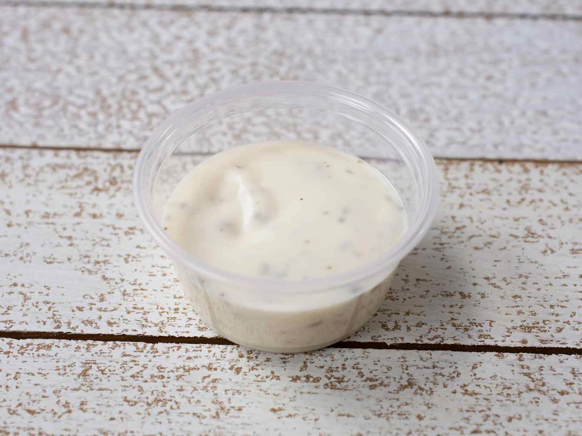 Herbed ranch dressing in a blue-rimmed bowl viewed from above.