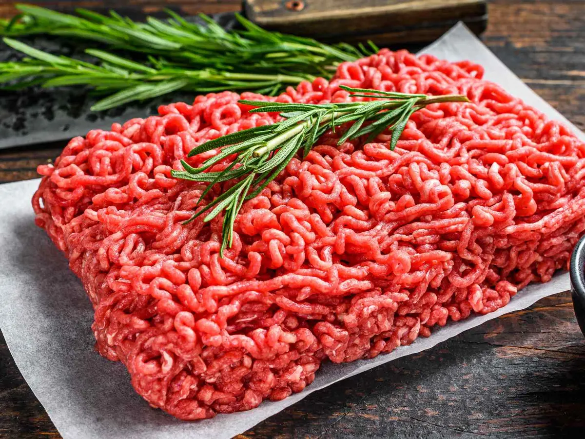 Raw ground beef arranged with rosemary and peppercorns